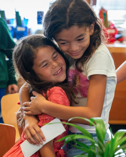 Two people embracing in a classroom.